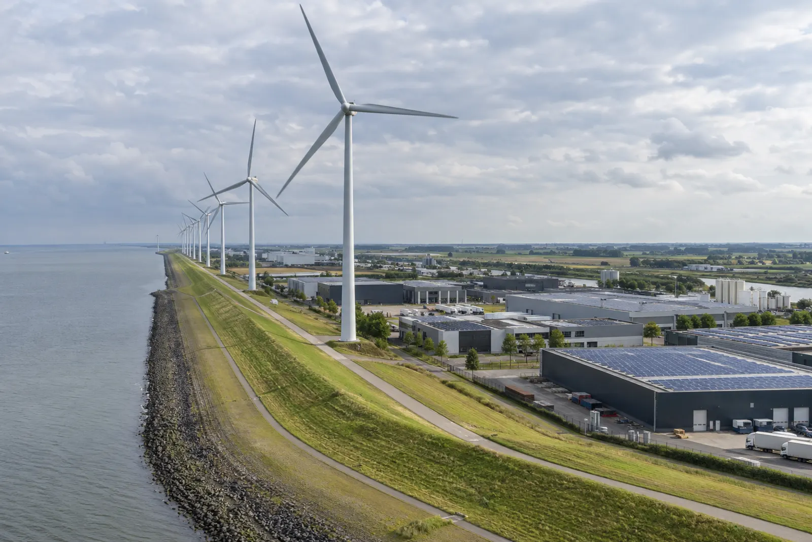 Windturbines op een dijk naast een bedrijventerrein